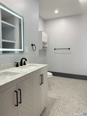 a view of bathroom with a sink mirror and cabinets