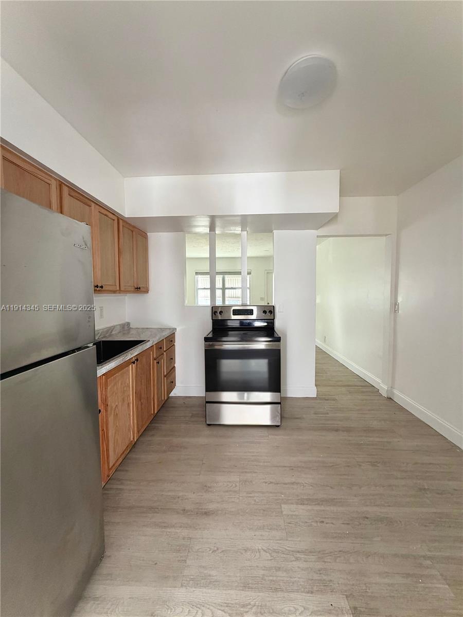 224 Southwest 10th Street, Unit 1 Hallandale Beach, FL 33009 - Photo 6 of 22 a kitchen with granite countertop a refrigerator and a stove
