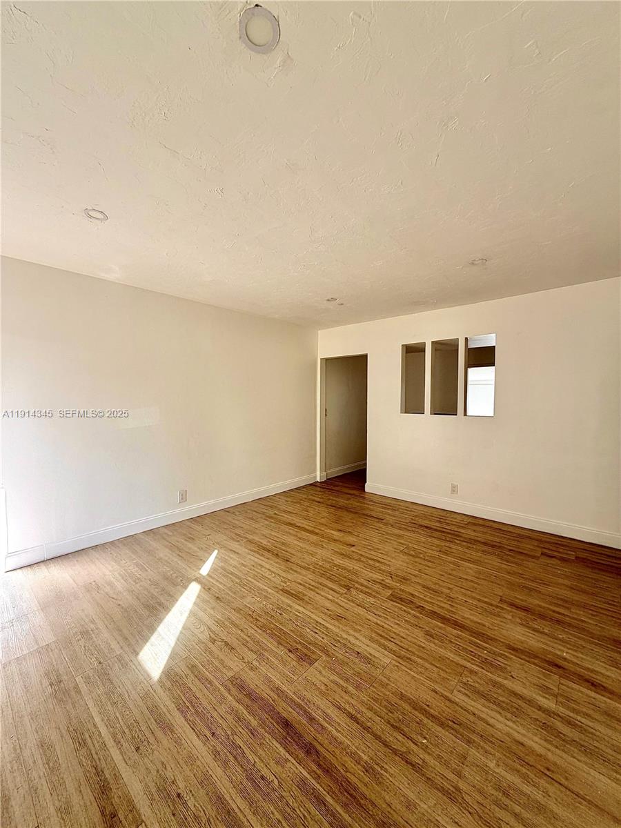 224 Southwest 10th Street, Unit 1 Hallandale Beach, FL 33009 - Photo 9 of 22 a view of an empty room with wooden floor and a window