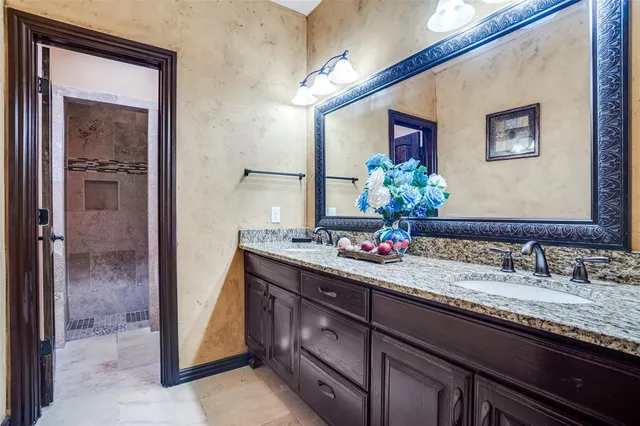 a bathroom with a granite countertop sink a large mirror and a shower
