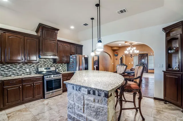 a kitchen with stainless steel appliances granite countertop a stove top oven a sink island and chairs