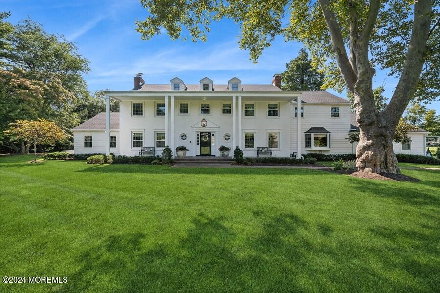 a view of a white house with a big yard and large trees