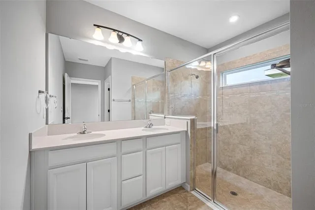 a bathroom with a sink shower and a mirror