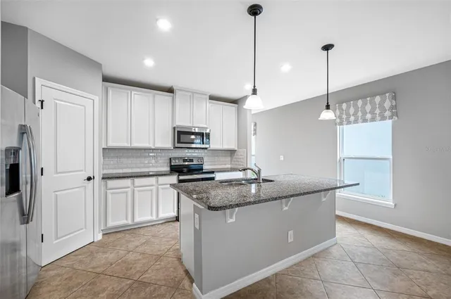 a kitchen with stainless steel appliances granite countertop a sink a stove a refrigerator and island with wooden floor