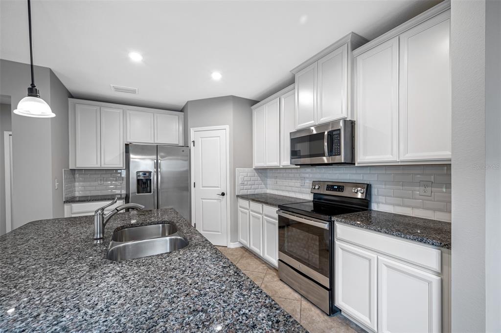 11230 High Noon Trail Parrish, FL 34219 - Photo 10 of 40 a kitchen with stainless steel appliances granite countertop a sink a stove a microwave and a refrigerator