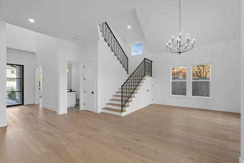 a view of an empty room with wooden floor and a chandelier