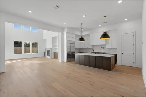a large kitchen with stainless steel appliances granite countertop a large counter top a sink and a refrigerator