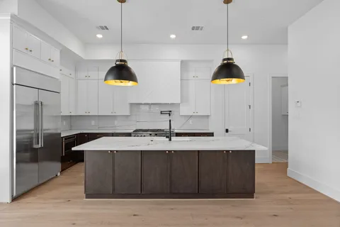 a kitchen with kitchen island stainless steel appliances a sink a center island a stove and a window