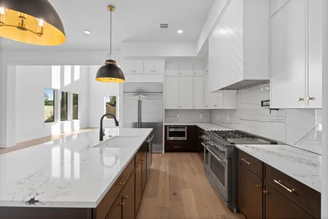 a kitchen with kitchen island stainless steel appliances a sink a stove and a wooden floors