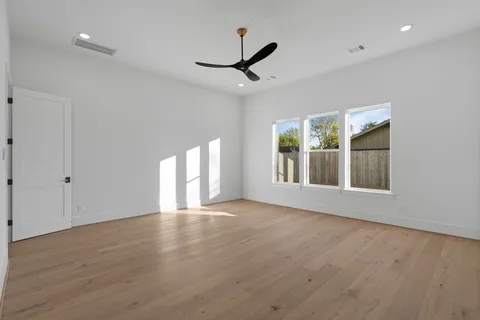 a view of an empty room with a window and wooden floor