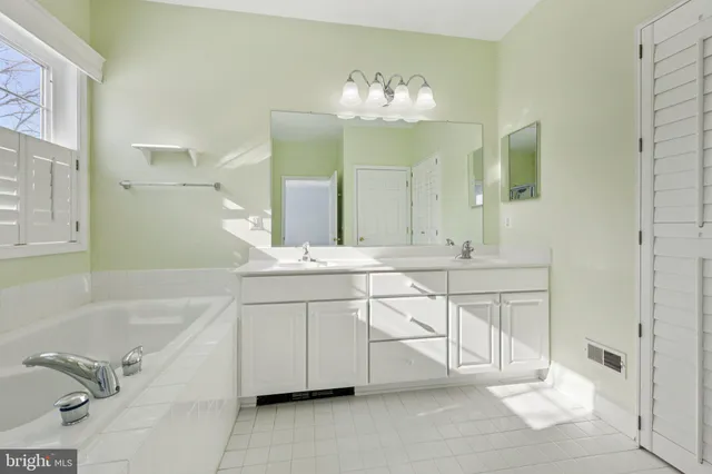 a spacious bathroom with a double vanity sink mirror and bathtub