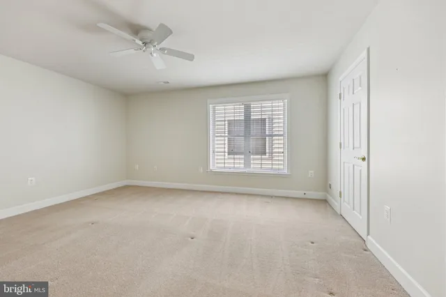 an empty room with windows and chandelier fan