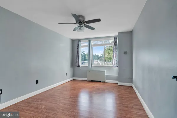 a view of empty room with wooden floor and fan