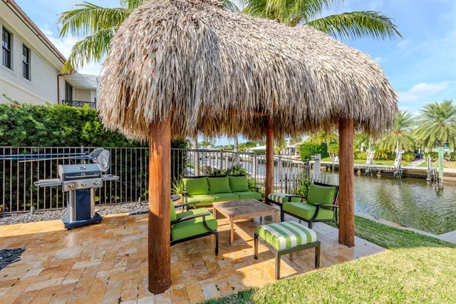 a backyard of a house with table and chairs under an umbrella