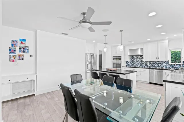 a kitchen with granite countertop white cabinets white appliances with wooden floor