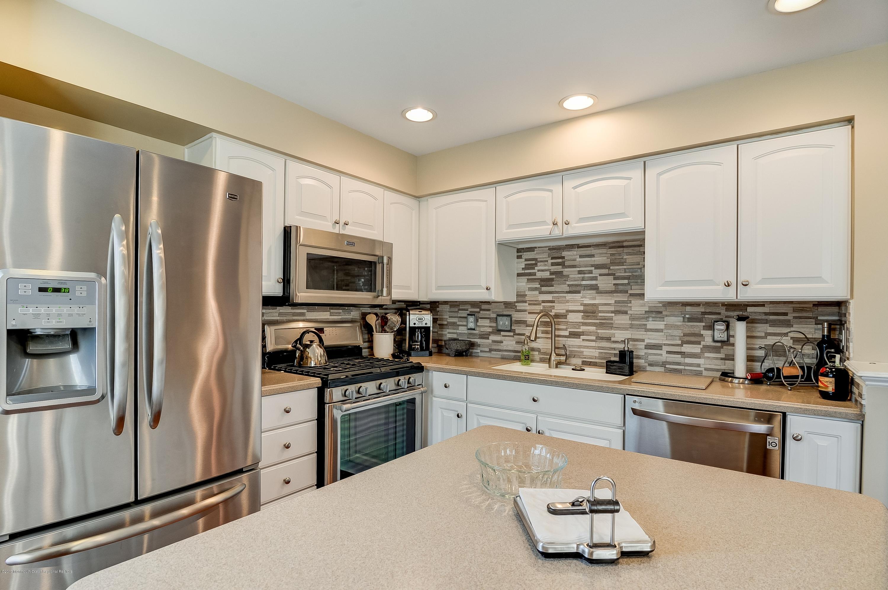 31 Saxton Road, Unit 53 Farmingdale, NJ 07727 - Photo 11 of 25 a kitchen with stainless steel appliances a sink a stove a refrigerator cabinets and a counter top space