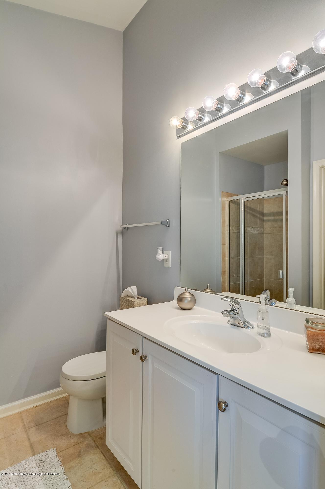 31 Saxton Road, Unit 53 Farmingdale, NJ 07727 - Photo 17 of 25 a bathroom with a granite countertop sink a toilet and a mirror