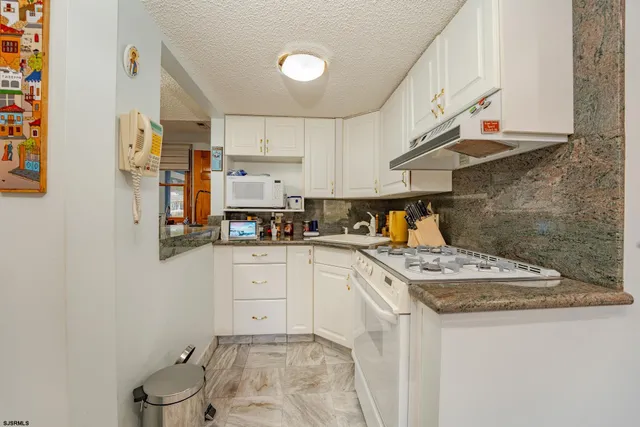 a view of a kitchen with stainless steel appliances granite countertop a sink and a counter top space