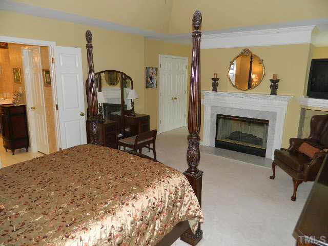 9108 Breeland Way Raleigh, NC 27613 - Photo 12 of 25 a bedroom with a bed dresser and a fireplace