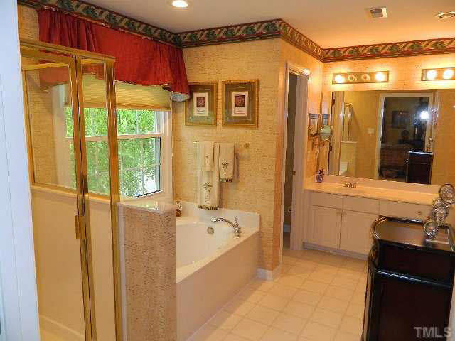 9108 Breeland Way Raleigh, NC 27613 - Photo 15 of 25 a bathroom with a tub a sink and a large mirror