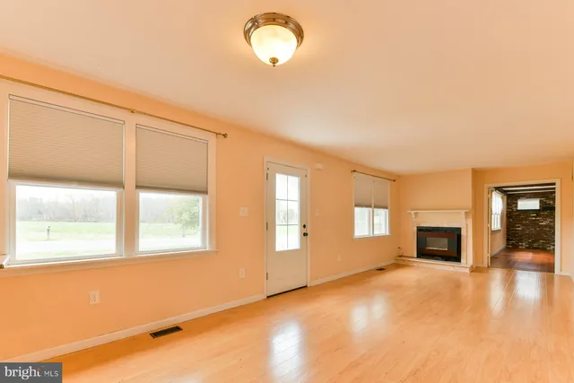 a view of an empty room with a window and fire place
