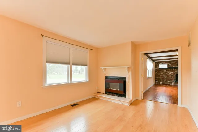a view of an empty room with a fireplace and a window