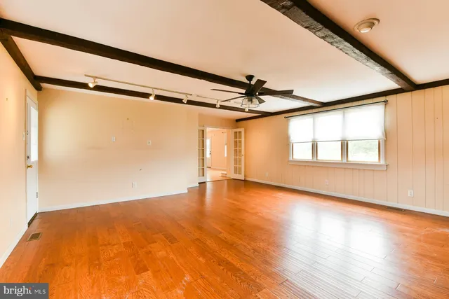 a view of empty room with wooden floor and fan