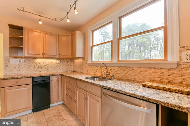 a kitchen with granite countertop sink window and cabinets