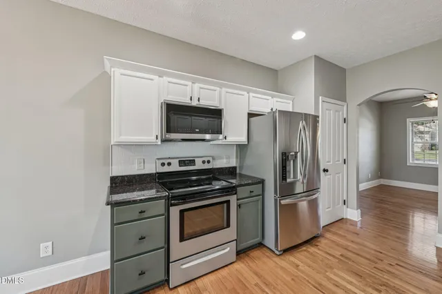 a kitchen with a refrigerator stove and wooden floor