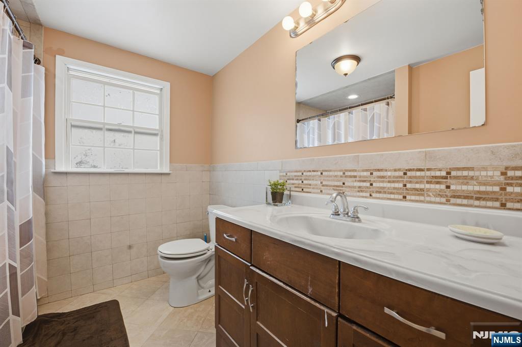 41 Woodland Road Bloomfield, NJ 07003 - Photo 18 of 27 a bathroom with a sink a toilet and a mirror