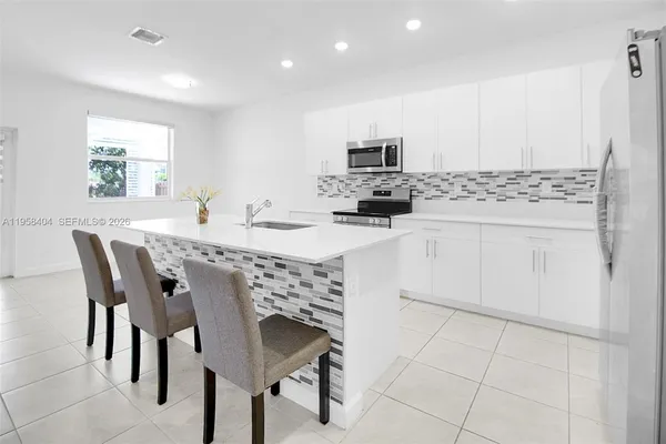 a kitchen with stainless steel appliances a white table chairs and a refrigerator