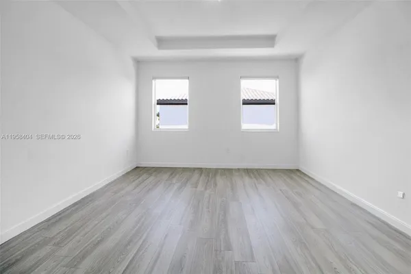 an empty room with a hardwood and windows