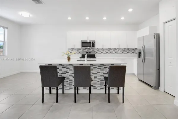 a kitchen with a dining table chairs refrigerator and cabinets