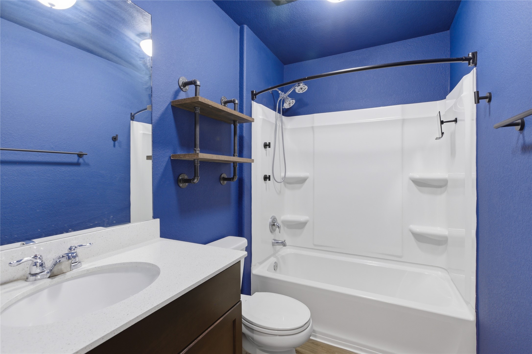 116 Night Riders Way Jarrell, TX 76537 - Photo 31 of 40 Bathroom featuring a white vanity with an integrated sink and chrome faucet, a white tub-shower combination with a curved shower rod, a toilet, and wall-mounted shelving with pipe accents