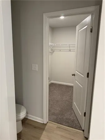 a view of empty room with wooden floor and bathroom
