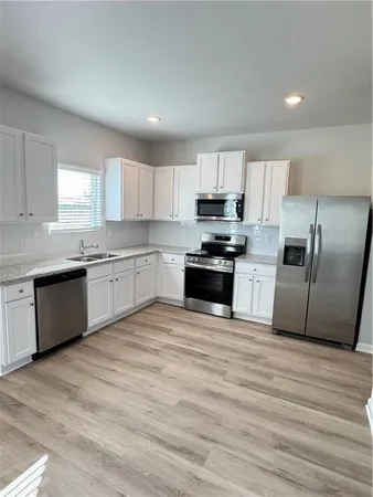 a large kitchen with cabinets stainless steel appliances a sink and a window