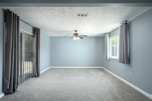an empty room with windows and ceiling fan