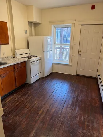 a kitchen with granite countertop wooden floors and white stainless steel appliances