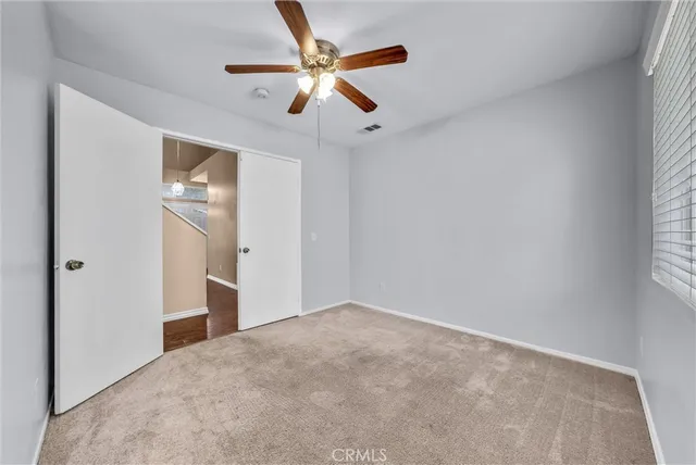 an empty room with closet and a chandelier fan