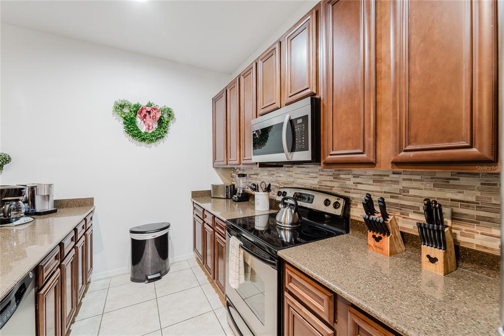 8961 Majesty Palm Road Kissimmee, FL 34747 - Photo 11 of 40 a kitchen with stainless steel appliances granite countertop a sink stove and cabinets