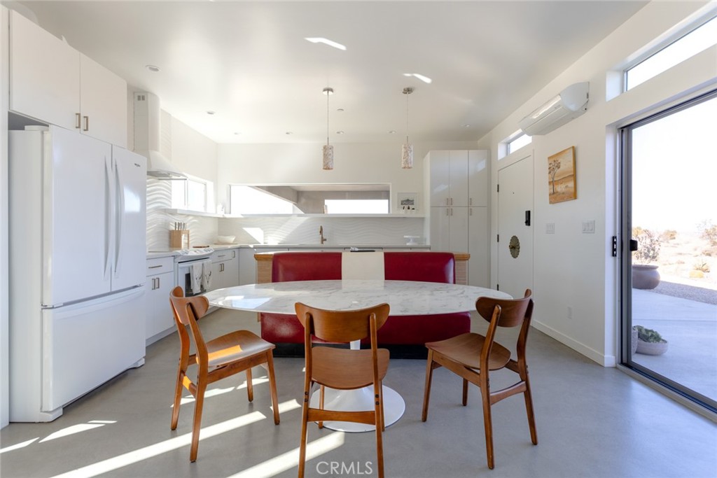7802 Quail Springs Road Joshua Tree, CA 92252 - Photo 6 of 46 a dining room with stainless steel appliances kitchen island granite countertop a dining table chairs and a refrigerator