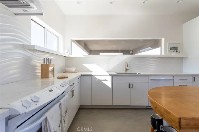 a view of cabinets a sink and a potted plant sitting on a granite counter top