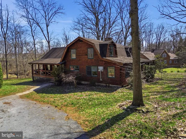 a front view of a house with a yard covered with trees