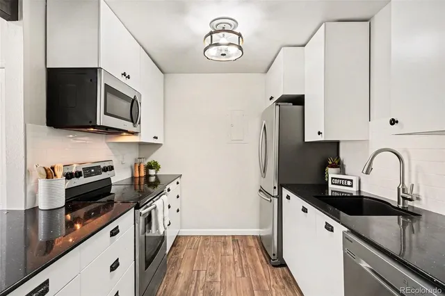 a kitchen with stainless steel appliances a sink dishwasher a refrigerator microwave and stove with wooden floor