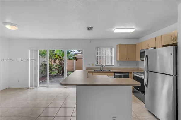 a kitchen with stainless steel appliances granite countertop a refrigerator a sink a stove a microwave and a refrigerator