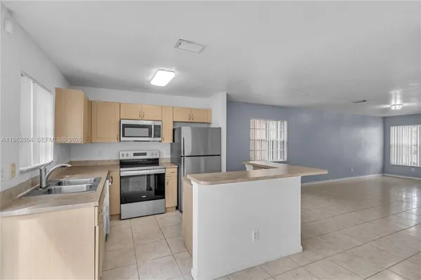 a kitchen with stainless steel appliances granite countertop a sink stove refrigerator and cabinets