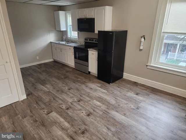 a kitchen with granite countertop a refrigerator and a stove top oven