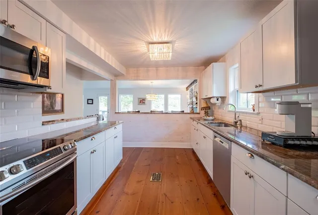 a large kitchen with stainless steel appliances granite countertop a stove a sink and a microwave