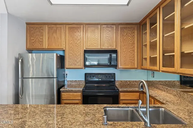 a kitchen with granite countertop wooden cabinets and a refrigerator