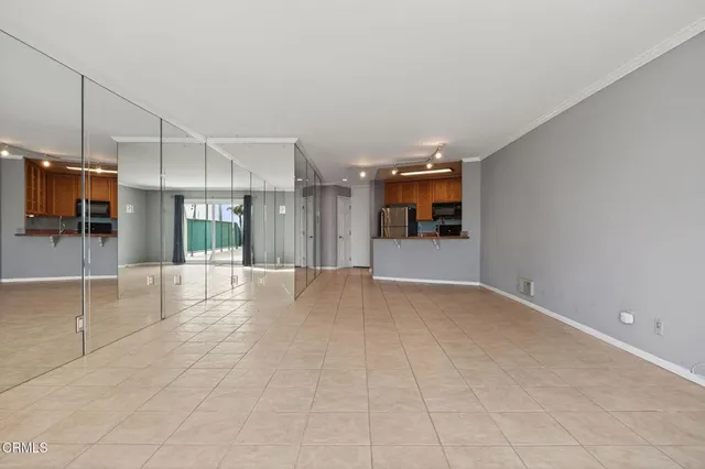 a view of an empty room with kitchen and a window